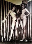 Two fully naked girls standing against striped wall